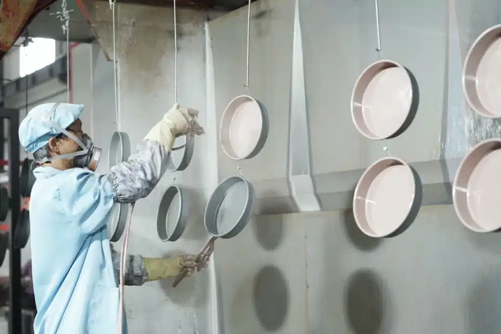 a professional worker doing nonstick coating spraying in the metal baking products factory